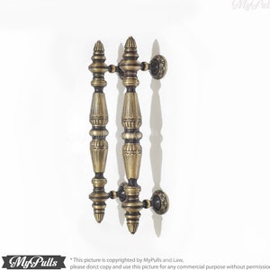 Puede incluir: Un par de tiradores de puerta de latón antiguo con detalles ornamentados. Los tiradores están diseñados para ser utilizados en ambos lados de una puerta.