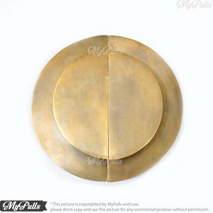 May include: A pair of round, brass door pulls with a concentric circle design. The pulls are separated and ready to be installed on a door.