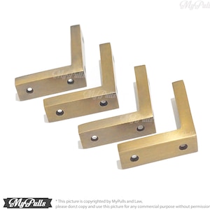 Puede incluir: Cuatro escuadras de esquina en forma de L, de color latón, con agujeros pretaladrados. Las escuadras están dispuestas en diagonal sobre un fondo blanco. La imagen incluye el logotipo de MyPulls e información de derechos de autor.