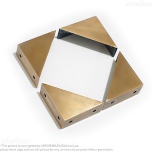 May include: Four gold-toned metal corner brackets in a triangular shape. Each bracket has three holes for attaching to furniture.