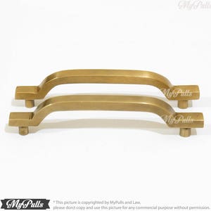 Op de afbeelding: Twee messing kastgrepen met een gebogen ontwerp. De grepen zijn ongeveer 12,7 cm lang en hebben een vierkante vorm aan de uiteinden.