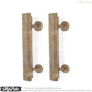 May include: Two antique brass door pulls with a wood grain texture. The pulls are mounted on a white background.