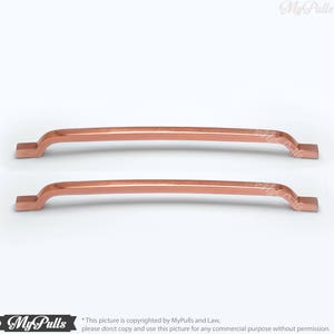 May include: Two copper cabinet pulls with a square end and a slight curve. The pulls are shown against a white background.