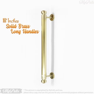 May include: An 18-inch solid brass long door handle with rounded ends. The handle is mounted to a white wall.