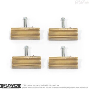 May include: Four antique brass cabinet pulls with a rectangular shape and a slightly curved design. Each pull has a single screw for installation.