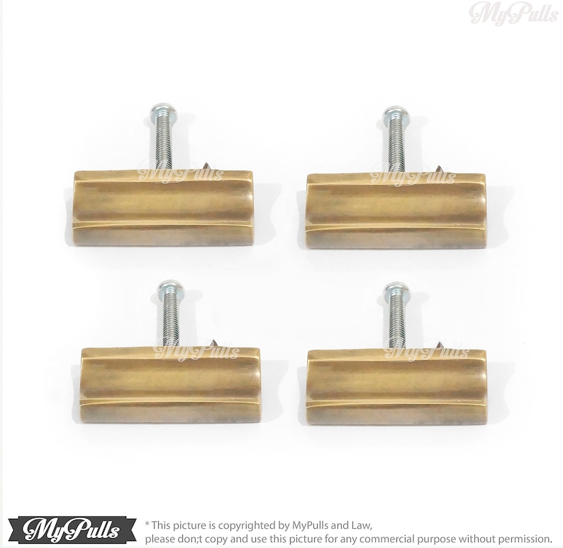 May include: Four antique brass cabinet pulls with a rectangular shape and a slightly curved design. Each pull has a single screw for installation.