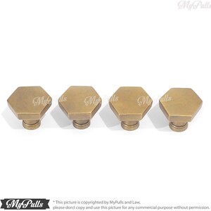 Puede incluir: Cuatro pomos hexagonales de armario de lat&oacute;n antiguo con una parte superior ligeramente redondeada.