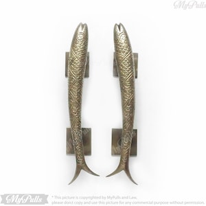 May include: A pair of antique brass door handles shaped like fish with detailed scales and a textured finish.