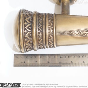 Puede incluir: Una manilla de puerta de lat&oacute;n con un dise&ntilde;o ornamentado. La manilla mide aproximadamente 15 cm de largo y tiene un pomo redondo en un extremo. La manilla est&aacute; hecha de lat&oacute;n macizo y tiene un acabado pulido.
