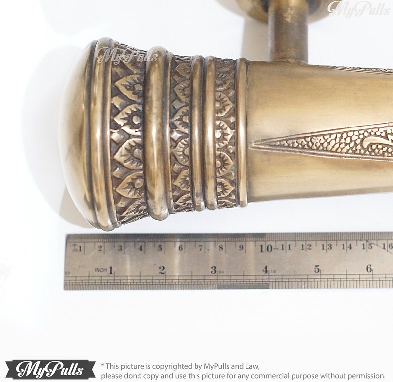 Puede incluir: Una manilla de puerta de lat&oacute;n con un dise&ntilde;o ornamentado. La manilla mide aproximadamente 15 cm de largo y tiene un pomo redondo en un extremo. La manilla est&aacute; hecha de lat&oacute;n macizo y tiene un acabado pulido.
