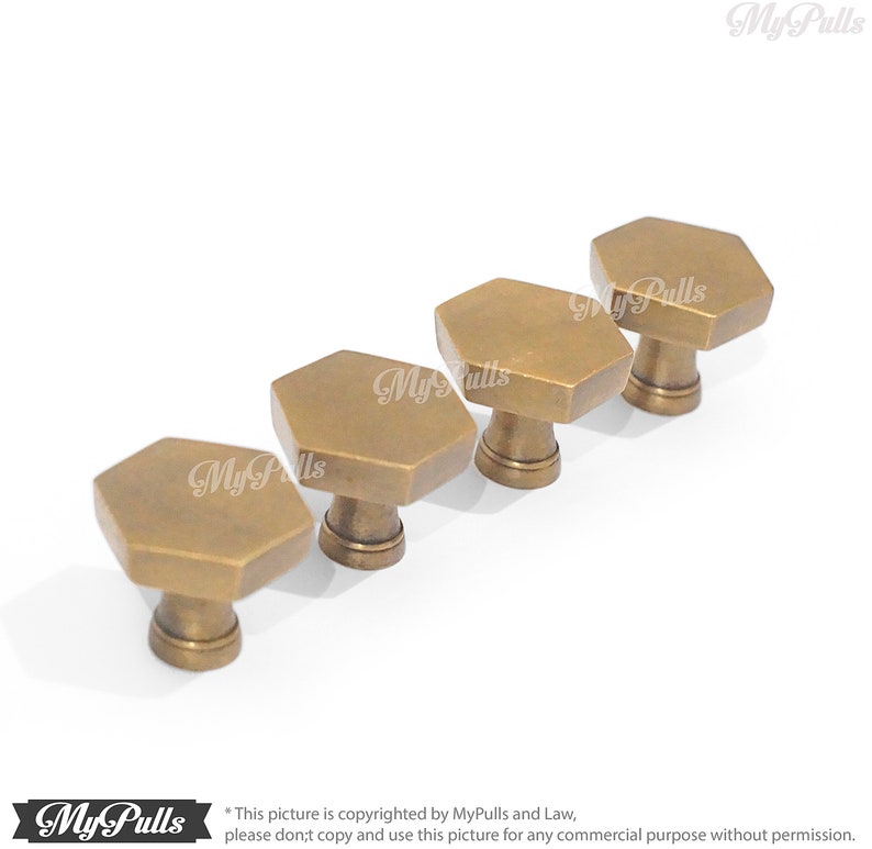 Puede incluir: Cuatro pomos hexagonales de armario de lat&oacute;n antiguo. Los pomos est&aacute;n dispuestos en fila, con el pomo m&aacute;s grande en la parte posterior y el pomo m&aacute;s peque&ntilde;o en la parte delantera.