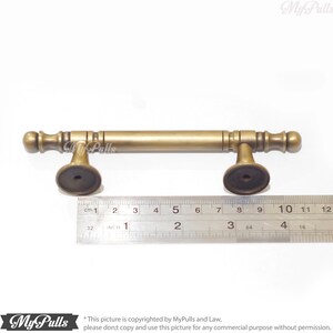 Pode incluir: Um puxador de arm&aacute;rio bronzeado com uma barra cil&iacute;ndrica e pe&ccedil;as finais decorativas. O puxador mede aproximadamente 12,7 cm de comprimento. O puxador tem um design cl&aacute;ssico e &eacute; adequado para restaura&ccedil;&atilde;o de m&oacute;veis ou novas constru&ccedil;&otilde;es.