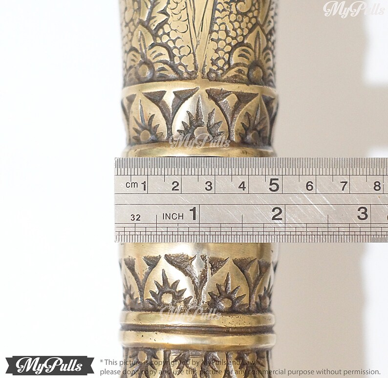 Puede incluir: Primer plano de un bast&oacute;n de metal dorado con intrincados dise&ntilde;os florales. Una regla se coloca junto al bast&oacute;n, mostrando que tiene 12,7 cm de largo.