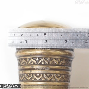 Puede incluir: Primer plano de un pomo de lat&oacute;n con un dise&ntilde;o ornamentado. El pomo tiene un di&aacute;metro de 5 pulgadas.