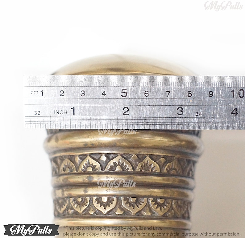 Puede incluir: Primer plano de un pomo de lat&oacute;n con un dise&ntilde;o ornamentado. El pomo tiene un di&aacute;metro de 5 pulgadas.