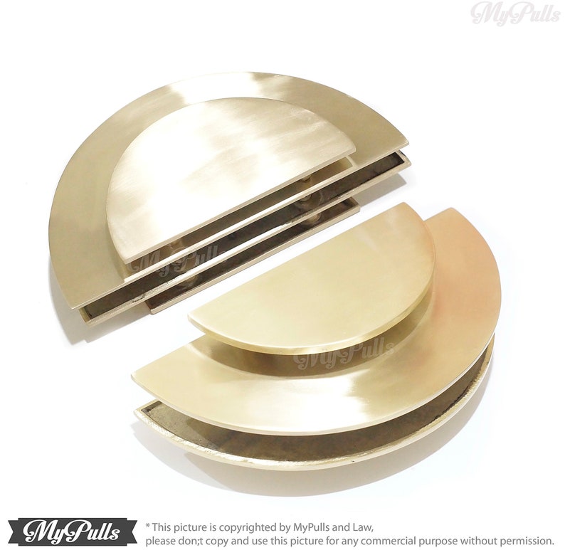 May include: Set of four gold-toned half-circle cabinet door pulls. The pulls are stacked on top of each other, with the largest pull on the bottom and the smallest pull on the top.