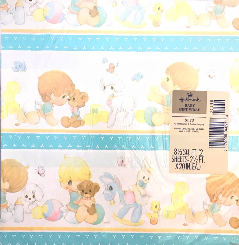 Op de afbeelding: Hallmark Baby Geschenkpapier met een blauw en geel patroon met illustraties van kinderen die met speelgoed spelen. De tekst op het etiket luidt "Hallmark Baby Geschenkpapier $ 1,70 8 1/3 sq. ft. (2 vellen: 2 1/2 ft. x 20 in. ea.)"