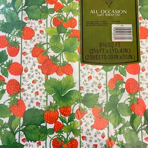 May include: Strawberry patterned gift wrap with a green label that says "Ambassador All Occasion Gift Wrap 59c" and includes the text "8 1/3 sq. ft. (2 1/2 ft. x 1 yd. 4 in.) (2 sheets - 30 in. x 20 in.)"