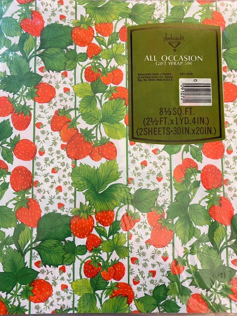 May include: Strawberry patterned gift wrap with a green label that says "Ambassador All Occasion Gift Wrap 59c" and includes the text "8 1/3 sq. ft. (2 1/2 ft. x 1 yd. 4 in.) (2 sheets - 30 in. x 20 in.)"