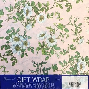 May include: Pink gift wrap with a floral pattern of white roses and green leaves. The text "Happy Birthday" is repeated throughout the design. The wrap is labeled "Gift Wrap" and "Birthday".