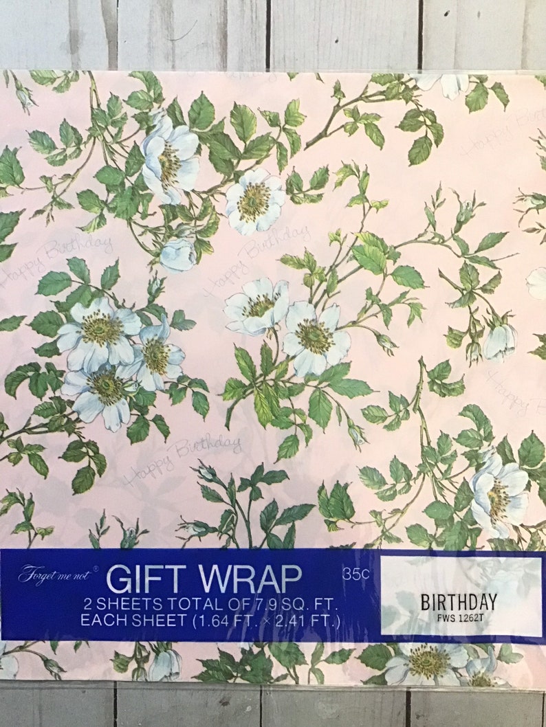 May include: Pink gift wrap with a floral pattern of white roses and green leaves. The text "Happy Birthday" is repeated throughout the design. The wrap is labeled "Gift Wrap" and "Birthday".