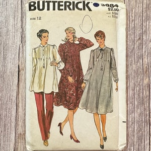 Può includere: Modello di cucito vintage per un abito con maniche lunghe e scollo arricciato. Il modello è per la taglia 12 ed è del modello Butterick numero 3984. Il modello costa $ 2,50.