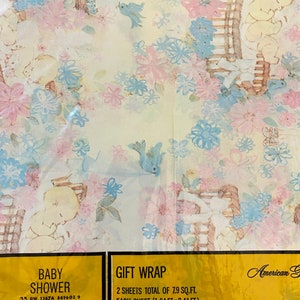 May include: A pastel blue and pink baby shower gift wrap with a floral pattern and a baby in a rocking chair. The text on the label reads "Baby Shower" and "Gift Wrap". 2 sheets total of 7.9 sq. ft. Each sheet (1.64 ft. x 2.41 ft.)