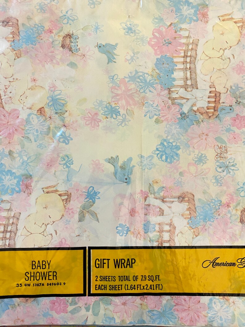 May include: A pastel blue and pink baby shower gift wrap with a floral pattern and a baby in a rocking chair. The text on the label reads "Baby Shower" and "Gift Wrap". 2 sheets total of 7.9 sq. ft. Each sheet (1.64 ft. x 2.41 ft.)