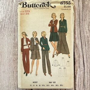 May include: Vintage sewing pattern for a women's trouser suit. The pattern is from the 1970s and features wide-legged trousers and a blazer with a collar and long sleeves. The pattern is for sizes 12-20 1/2.