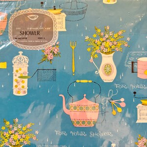 May include: Blue and white wrapping paper with a shower theme. The paper features a teapot, flowers, and kitchen tools. The text "For Your Shower" is repeated on the paper.