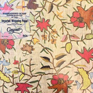 May include: A vintage wrapping paper design featuring a floral pattern with red, yellow, and green flowers on a cream background. The paper is labelled "Embroidered Scarf" and "Imported Wrapping Paper" with the text "Gaspari" and "60&cent;".