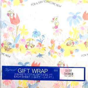 Op de afbeelding: Een blauw en roze cadeaupapier met een witte achtergrond. Het papier heeft een patroon van lieveheersbeestjes, bloemen en regendruppels. De tekst "Forget me not GIFT WRAP 2 SHEETS TOTAL OF 7.9 SQ. FT. EACH SHEET (1.64 FT. x 2.41 FT.) 50c BABY SHOWER FWS 1367 H" staat onderaan het papier gedrukt.