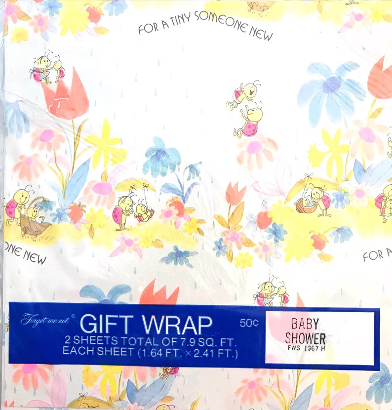 Op de afbeelding: Een blauw en roze cadeaupapier met een witte achtergrond. Het papier heeft een patroon van lieveheersbeestjes, bloemen en regendruppels. De tekst "Forget me not GIFT WRAP 2 SHEETS TOTAL OF 7.9 SQ. FT. EACH SHEET (1.64 FT. x 2.41 FT.) 50c BABY SHOWER FWS 1367 H" staat onderaan het papier gedrukt.