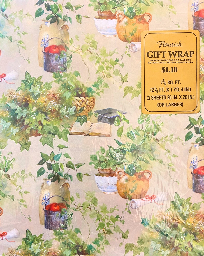 May include: Floral gift wrap with a beige background and a repeating pattern of green ivy, potted plants, and books. The text "Flourish Gift Wrap" is printed in gold on a yellow rectangle with the price "&pound;1.10" and the size "7 1/2 sq. ft. (2 1/2 ft. x 1 yd. 4 in.) (2 sheets 26 in. x 20 in.) (or larger)".