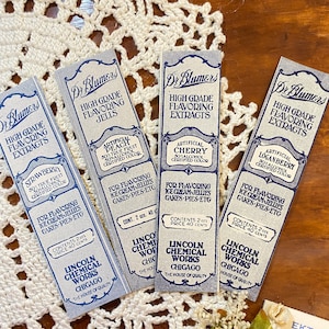 May include: Four vintage Dr. Blumer's flavoring extract labels. The labels are rectangular with a blue and white color scheme. Each label features text such as "High Grade Flavoring Extracts" and "Lincoln Chemical Works, Chicago."