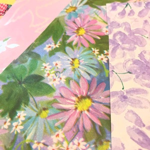 May include: A close-up of a floral patterned wrapping paper with pink, blue, and white flowers. The paper has a glittery finish.