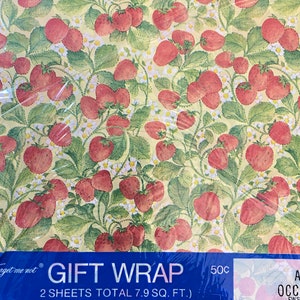 May include: A roll of gift wrap with a strawberry pattern on a yellow background. The text on the label reads "Forget me not GIFT WRAP 2 SHEETS TOTAL 7.9 SQ. FT. (EACH SHEET 2.41 FT. x 20 IN.) 50c".
