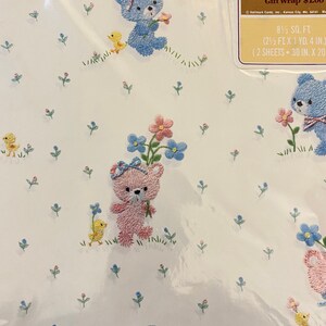 May include: A sheet of baby blue gift wrap with a white background and a repeating pattern of embroidered teddy bears, flowers, and chicks. The text "Baby Gift Wrap &pound;1.00" is printed on the label. 0.77 sq m (2.5 ft x 1 yd. 4 in.) (2 sheets - 76 cm x 51 cm)