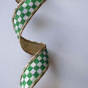 May include: A decorative ribbon featuring a vibrant green and white checkered pattern. The ribbon is twisted into a spiral shape and is finished with a metallic gold wire edge along both sides, providing structure and a shimmering border detail.