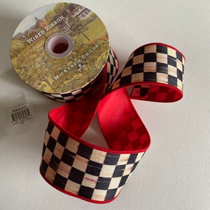 May include: A roll of wired ribbon with a black and white checkered pattern and red trim. The ribbon is from Mackenzie-Childs and is labeled "Wired Ribbon".