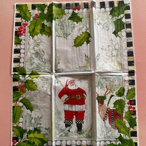 Puede incluir: Una servilleta de papel blanca con un borde a cuadros blanco y negro y un borde de acebo verde. La servilleta presenta una ilustraci&oacute;n de Pap&aacute; Noel y una ilustraci&oacute;n de reno. El texto "Feliz Navidad" est&aacute; impreso en la servilleta.