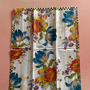 Puede incluir: Una servilleta de papel blanca con un dise&ntilde;o floral con flores azules, rojas, amarillas y verdes. La servilleta tiene un borde a cuadros blanco y negro.