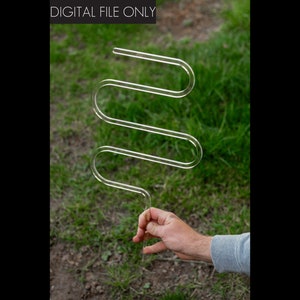 May include: A clear plastic S-shaped object with a long, thin handle. The object is being held in someone's hand.