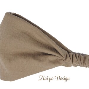 May include: A brown fabric headband with a gathered end. The headband is made of a soft, stretchy material and is designed to be worn around the head.