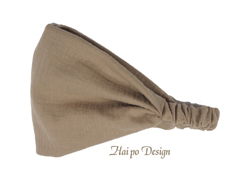 May include: A brown fabric headband with a gathered end. The headband is made of a soft, stretchy material and is designed to be worn around the head.