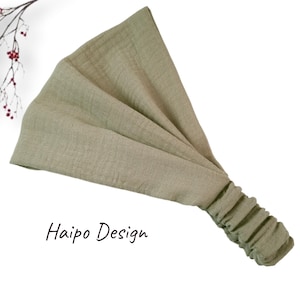 May include: A sage green fabric headband with a gathered elastic band. The headband is made of a soft, stretchy material and is perfect for keeping hair out of your face.