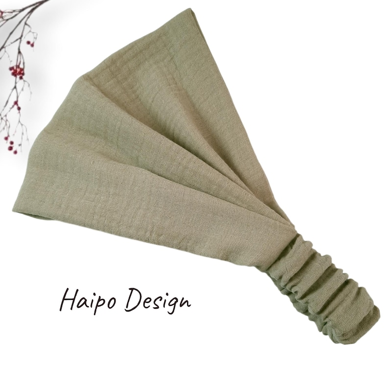 May include: A sage green fabric headband with a gathered elastic band. The headband is made of a soft, stretchy material and is perfect for keeping hair out of your face.