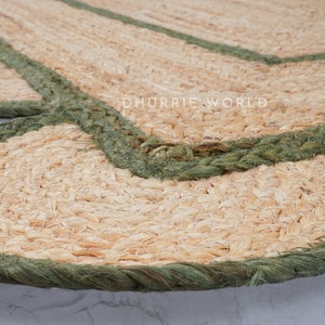 May include: A close-up of a jute rug with a scalloped edge and a green braided trim. The rug is made of natural fibers and has a rustic, earthy look.