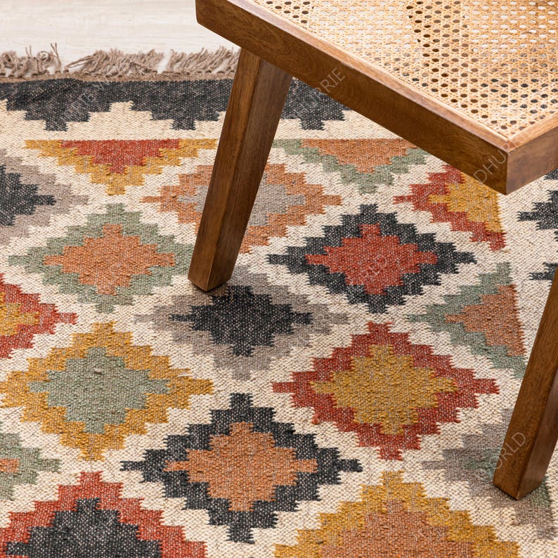 May include: A beige, brown, and black geometric patterned rug with a wooden stool with a woven cane seat.