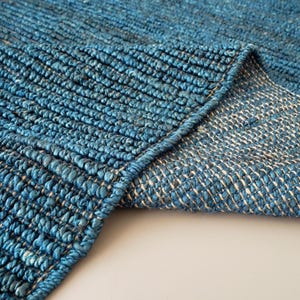 May include: A deep blue woven rug featuring a thick, textured corded surface on the top side and a contrasting lighter beige and blue cross-hatched weave on the underside, showing the construction of the heavy-duty textile material.